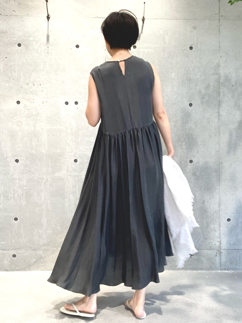 グレー系のワンピース、ベージュ系のサンダル、シルバー系のネックレスを着用したレディースの夏コーディネートの2枚目の写真