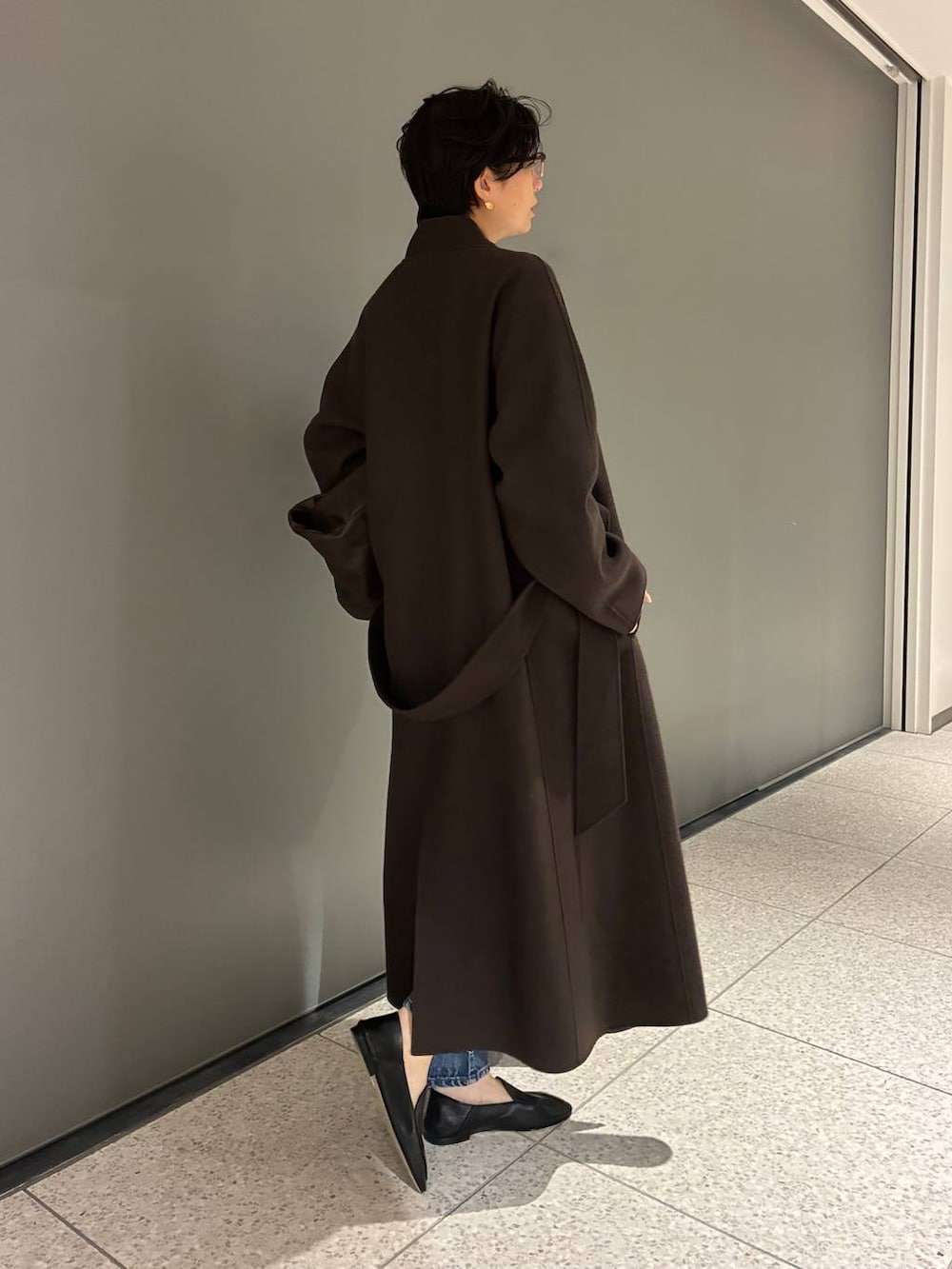 ブルー系のデニムパンツ、ブラウン系のニット/セーター、ブラウン系のノーカラーコートを着用したレディースの秋コーディネートの3枚目の写真