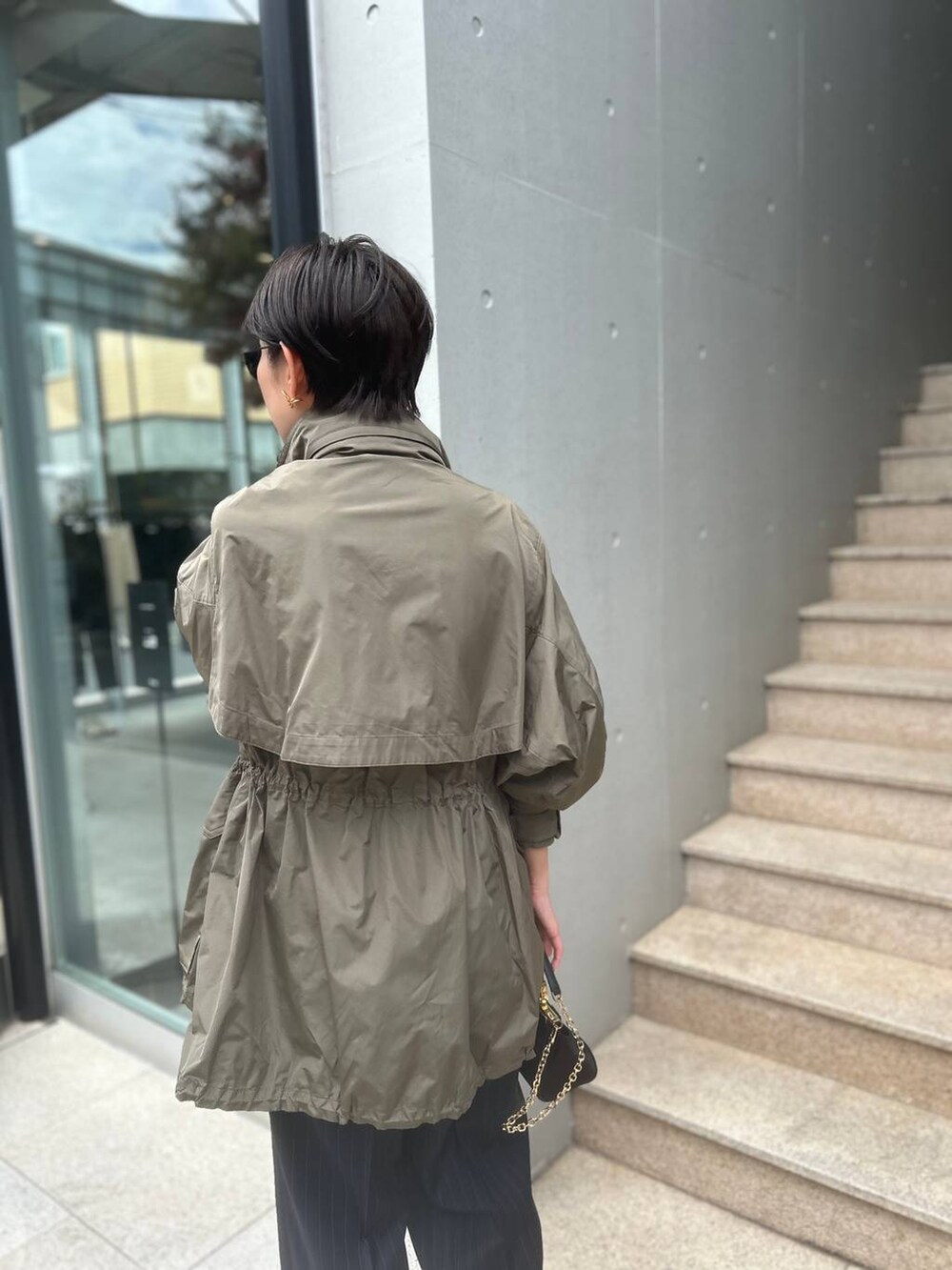 グレー系のTシャツ/カットソー、グリーン系のブルゾン、ブルー系のスラックスを着用したレディースの夏コーディネートの8枚目の写真