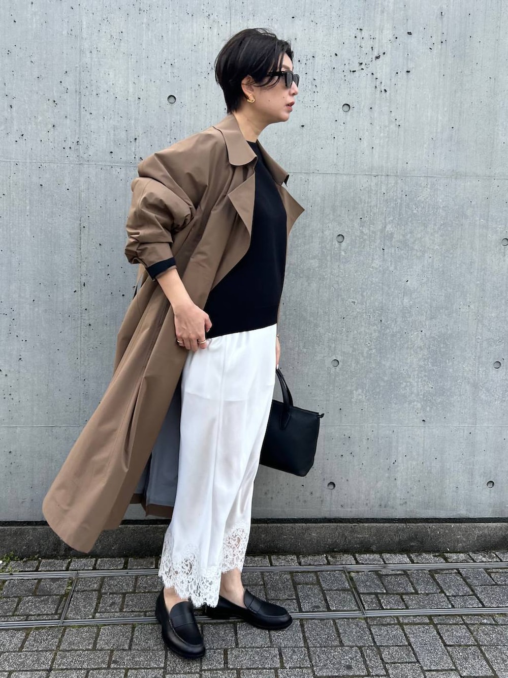 ブラック系のニット/セーター、ベージュ系のトレンチコートを着用したレディースの冬コーディネートの3枚目の写真