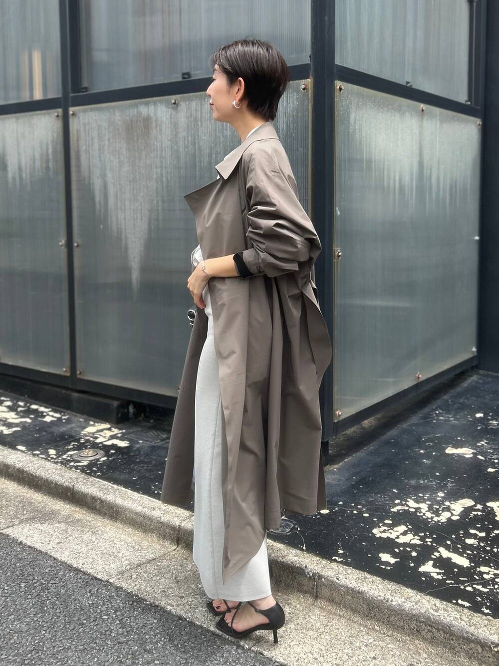 ベージュ系のシャツ/ブラウス、ブラウン系のトレンチコート、ブラック系のサンダルを着用したレディースの夏コーディネートの3枚目の写真
