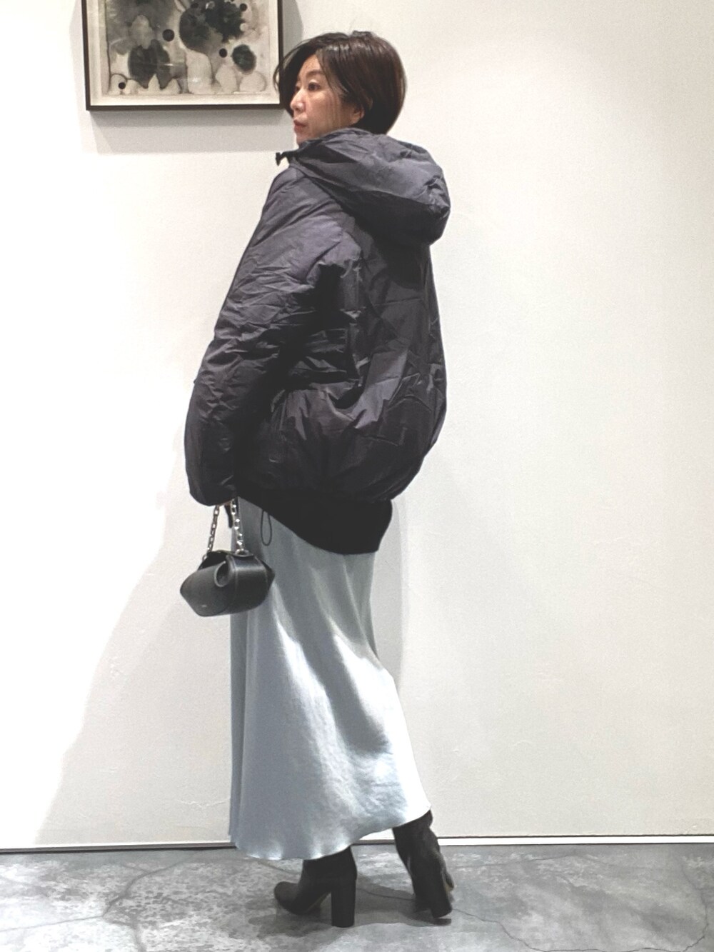 グリーン系のスカート、ブラック系のニット/セーター、グレー系のジャケット/アウターを着用したレディースの秋コーディネートの2枚目の写真