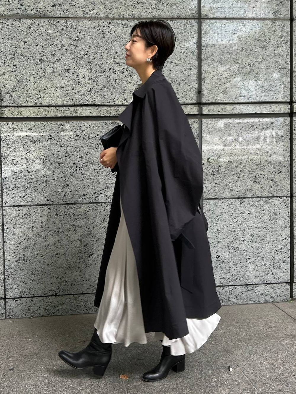 ブラック系のトレンチコート、グレー系のワンピースを着用したレディースの秋コーディネートの2枚目の写真
