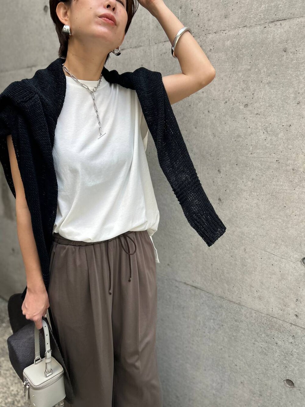 ホワイト系のTシャツ/カットソー、ブラック系のアンサンブル、ブラック系のサンダルを着用したレディースの春コーディネートの6枚目の写真