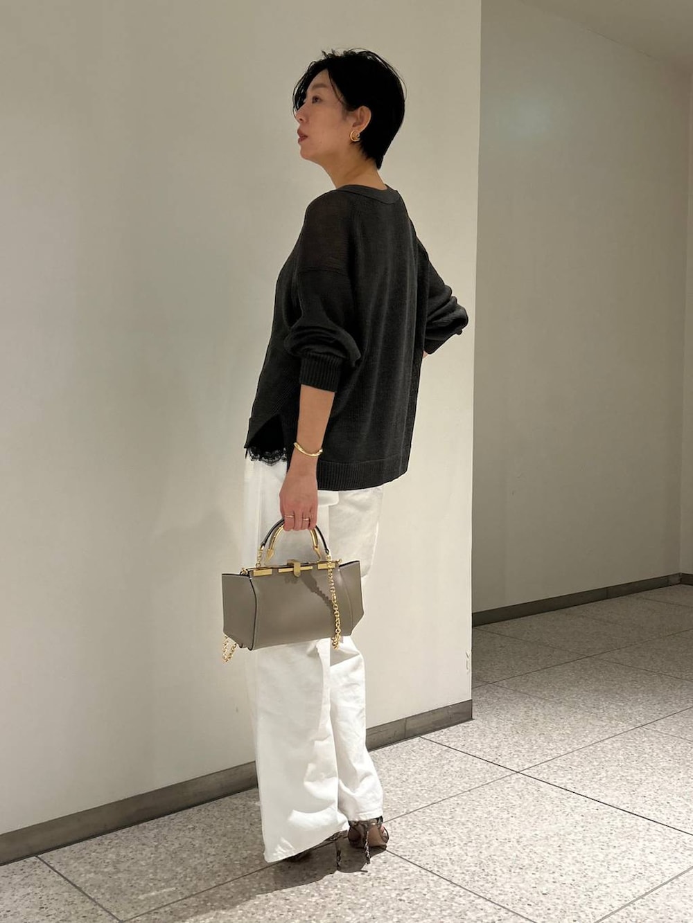 グリーン系のカーディガン/ボレロ、ホワイト系のデニムパンツ、グレー系のナイロンジャケットを着用したレディースの春コーディネートの3枚目の写真