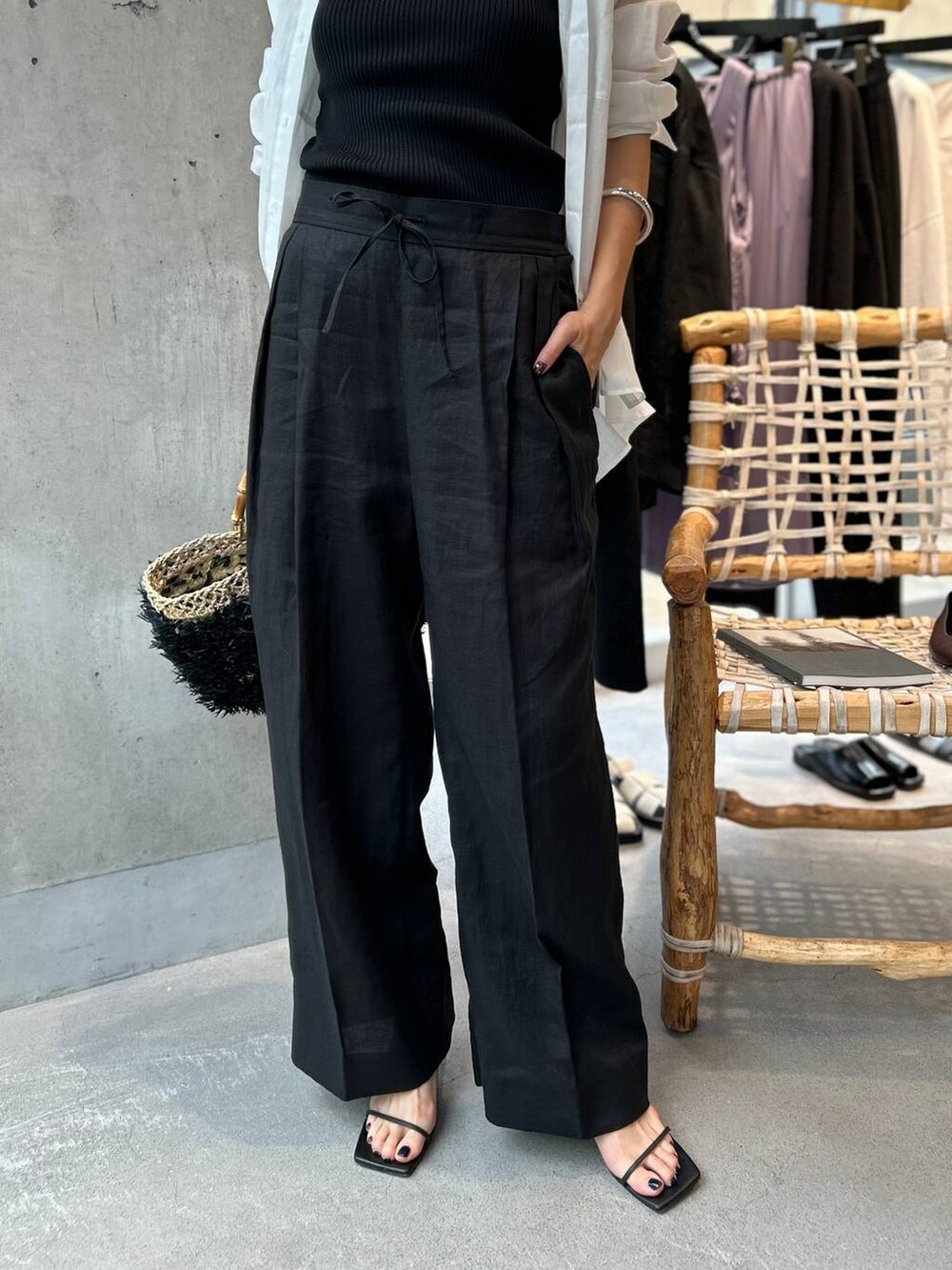 ブラック系のタンクトップ、ブラック系のかごバッグ、ブラック系のスラックスを着用したレディースの夏コーディネートの8枚目の写真