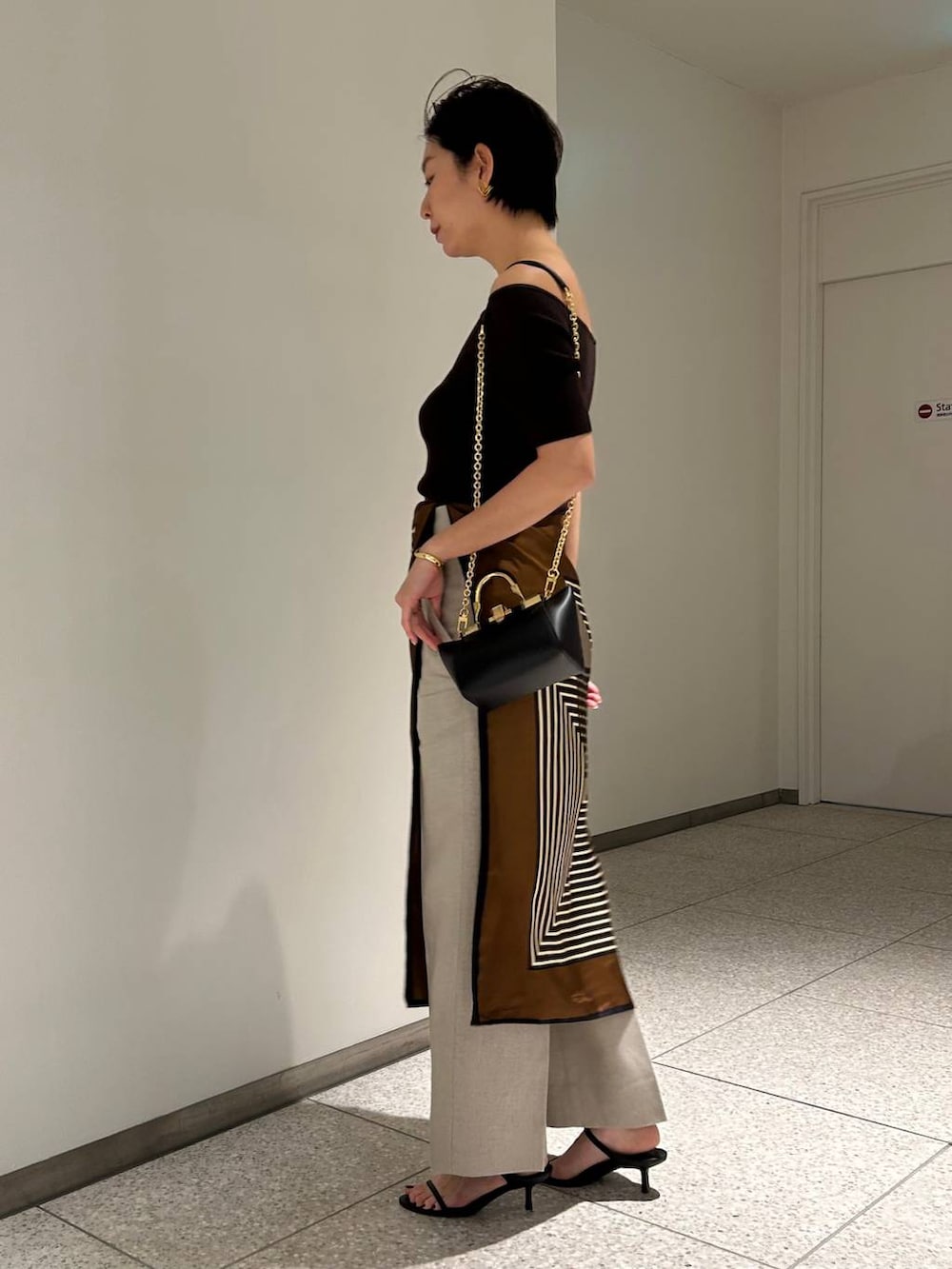 ホワイト系のスラックス、ブラウン系のTシャツ/カットソー、ブラウン系のバンダナ/スカーフを着用したレディースの春コーディネートの3枚目の写真