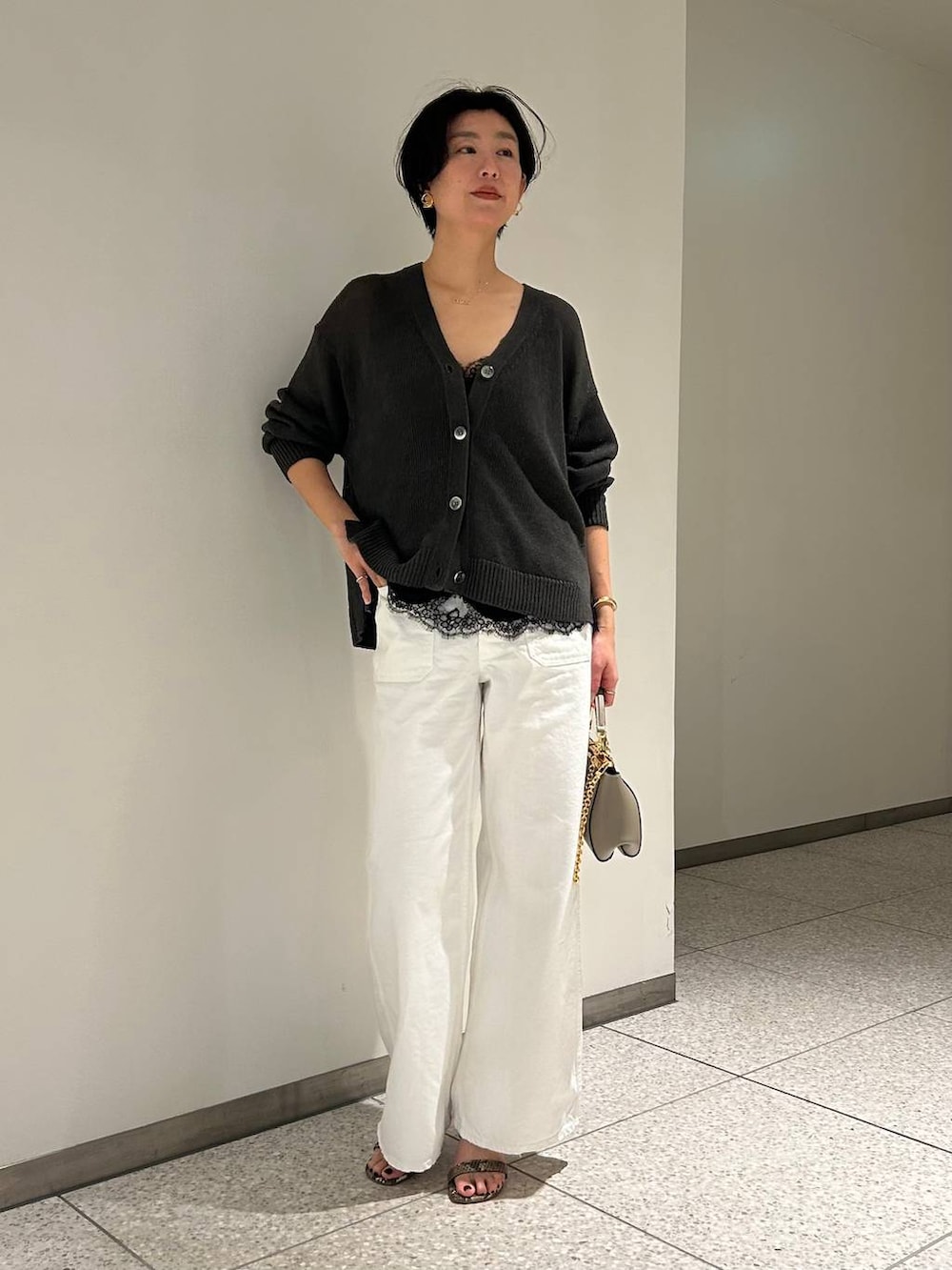 グリーン系のカーディガン/ボレロ、ホワイト系のデニムパンツ、グレー系のナイロンジャケットを着用したレディースの春コーディネートの2枚目の写真