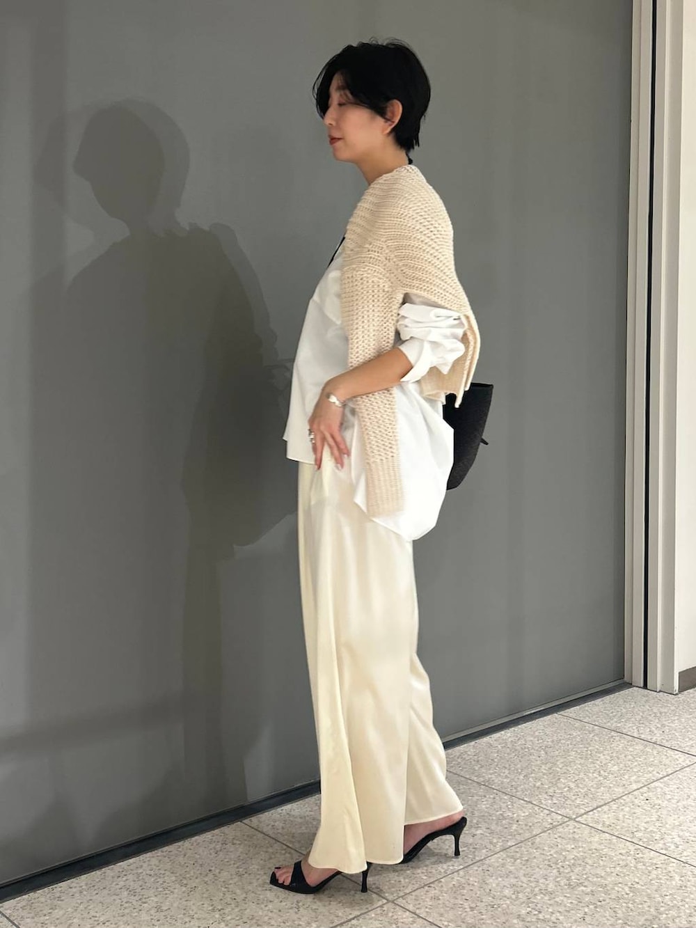 ホワイト系のニット/セーター、ホワイト系のシャツ/ブラウス、ブラック系のトレンチコートを着用したレディースの冬コーディネートの8枚目の写真