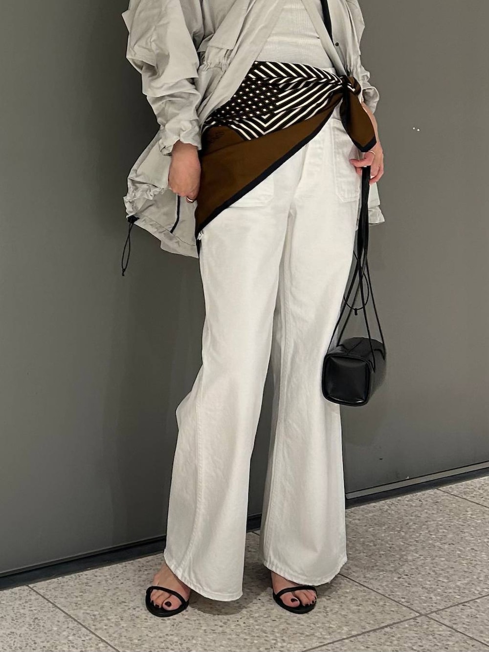 ホワイト系のデニムパンツ、ホワイト系のタンクトップ、グレー系のブルゾンを着用したレディースの春コーディネートの7枚目の写真