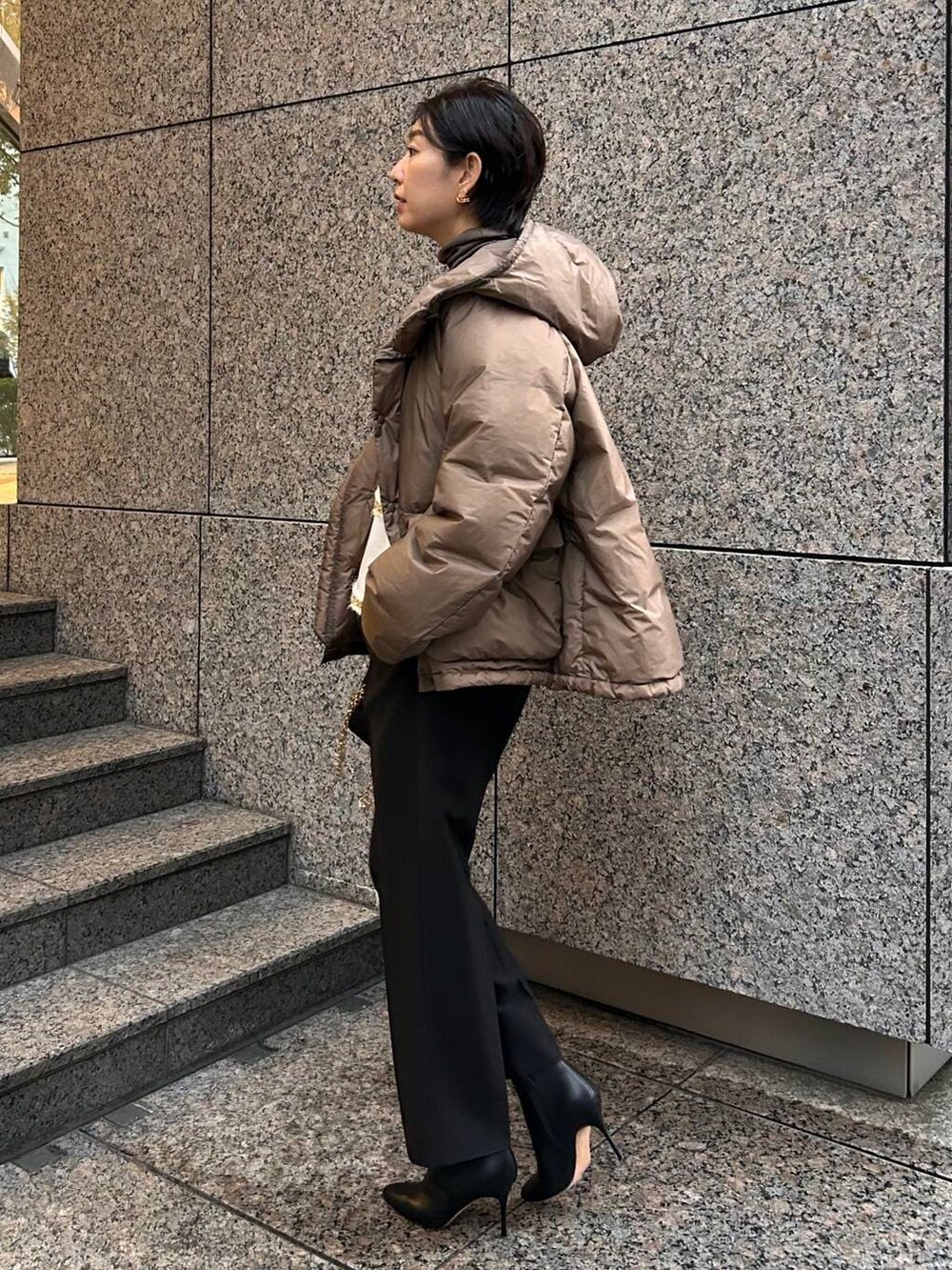 ベージュ系のニット/セーター、ブラウン系のダウンジャケット/コート、ブラック系のスラックスを着用したレディースの冬コーディネートの4枚目の写真