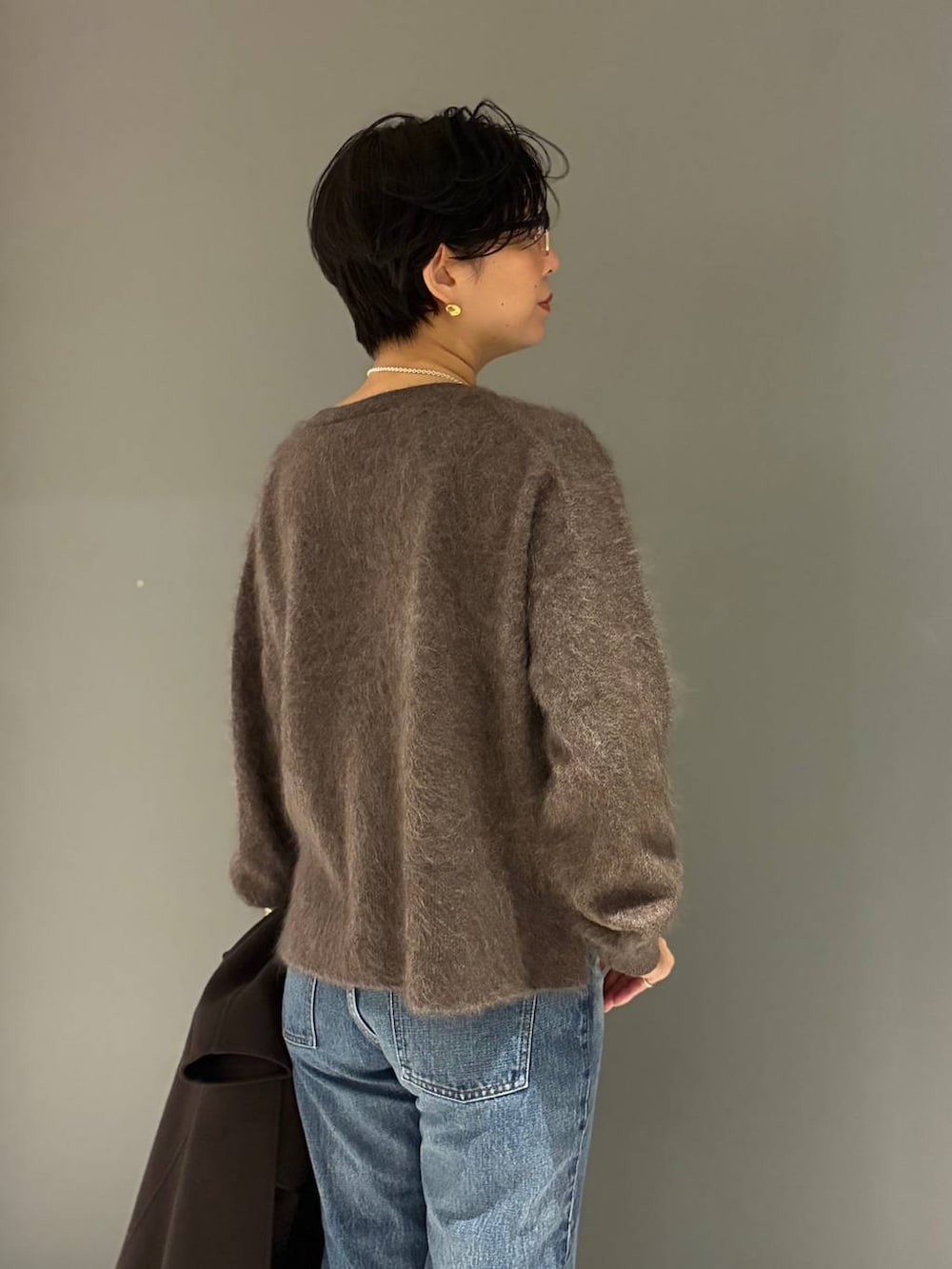 ブルー系のデニムパンツ、ブラウン系のニット/セーター、ブラウン系のノーカラーコートを着用したレディースの秋コーディネートの5枚目の写真
