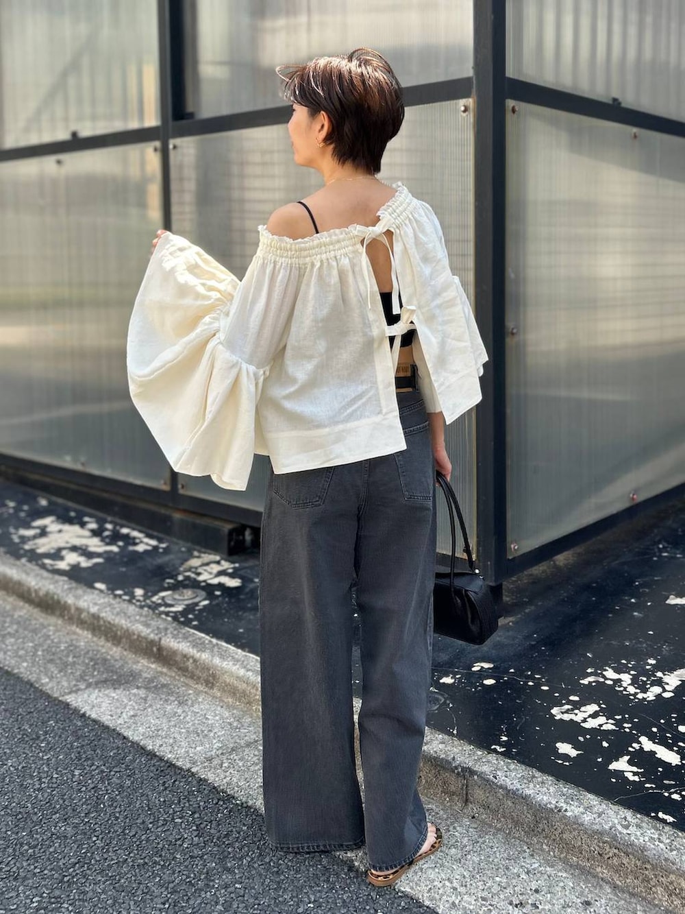 ブラック系のチューブトップ、ホワイト系のシャツ/ブラウス、ブラック系のデニムパンツを着用したレディースの春コーディネートの5枚目の写真