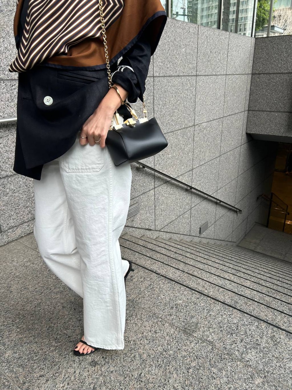 ホワイト系のデニムパンツ、ホワイト系のタンクトップ、ブラック系のテーラードジャケットを着用したレディースの春コーディネートの7枚目の写真