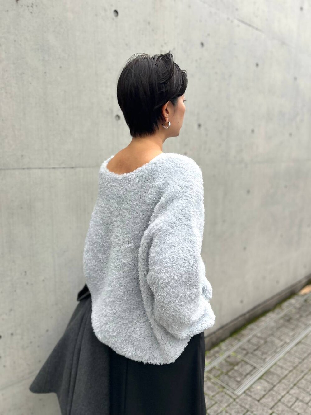 ブルー系のニット/セーター、グレー系のチェスターコート、ブラック系のスカートを着用したレディースの秋コーディネートの8枚目の写真