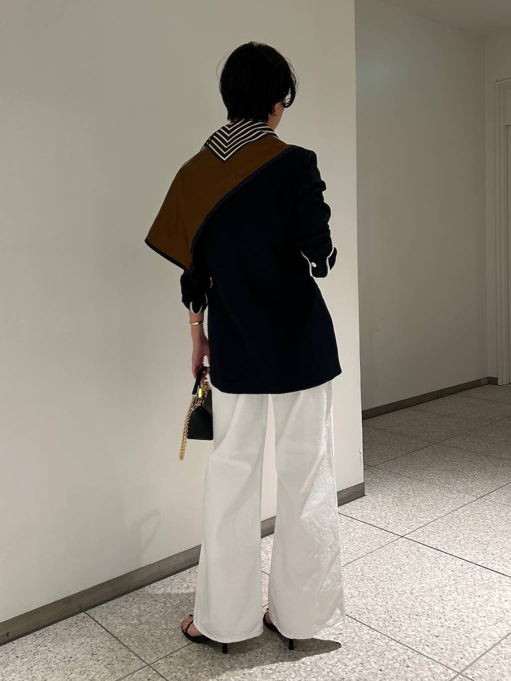 ホワイト系のデニムパンツ、ホワイト系のタンクトップ、ブラック系のテーラードジャケットを着用したレディースの春コーディネートの4枚目の写真