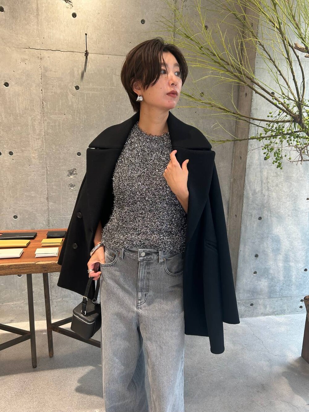グレー系のデニムパンツ、ブラック系のピーコート、シルバー系のニット/セーターを着用したレディースの秋コーディネートの6枚目の写真