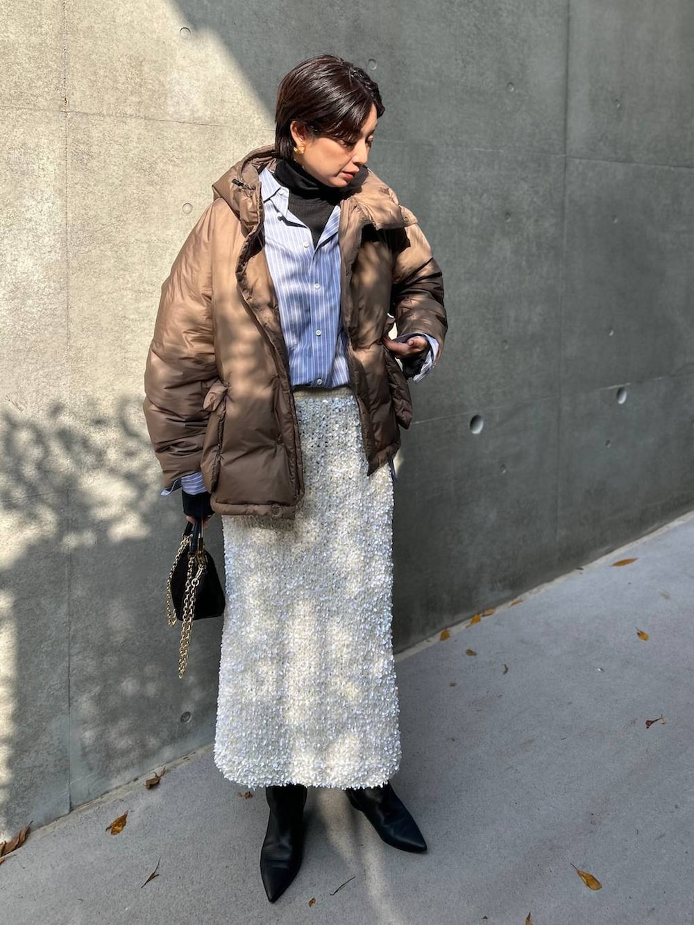 ブラック系のニット/セーター、ブルー系のシャツ/ブラウス、ブラウン系のダウンジャケット/コートを着用したレディースの冬コーディネートの3枚目の写真