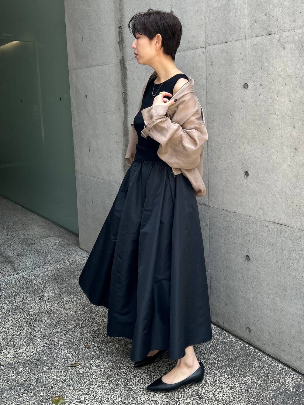 グレー系のブルゾン、ブラック系のスカート、ブラウン系のニット/セーターを着用したレディースの春コーディネートの2枚目の写真