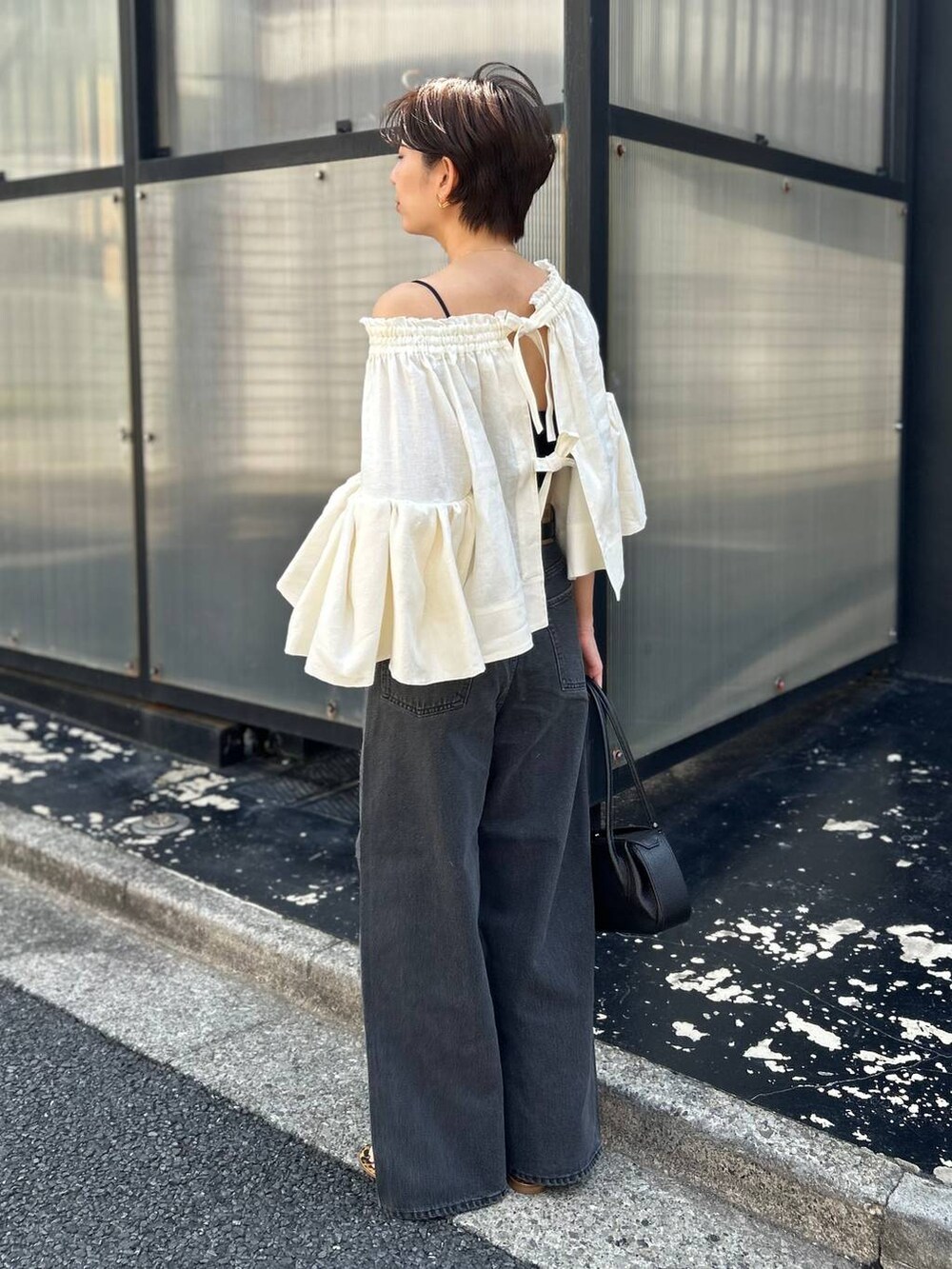 ブラック系のチューブトップ、ホワイト系のシャツ/ブラウス、ブラック系のデニムパンツを着用したレディースの春コーディネートの4枚目の写真