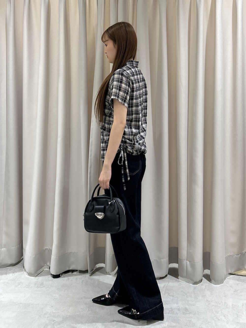ブルー系のデニムパンツ、ブラック系のシャツ/ブラウス、ブラック系のハンドバッグを着用したレディースの夏コーディネートの2枚目の写真