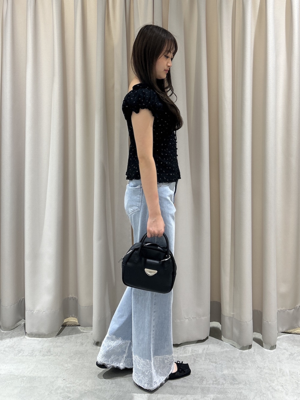 ブルー系のデニムパンツ、ブラック系のTシャツ/カットソー、ブラック系のハンドバッグを着用したレディースの夏コーディネートの3枚目の写真