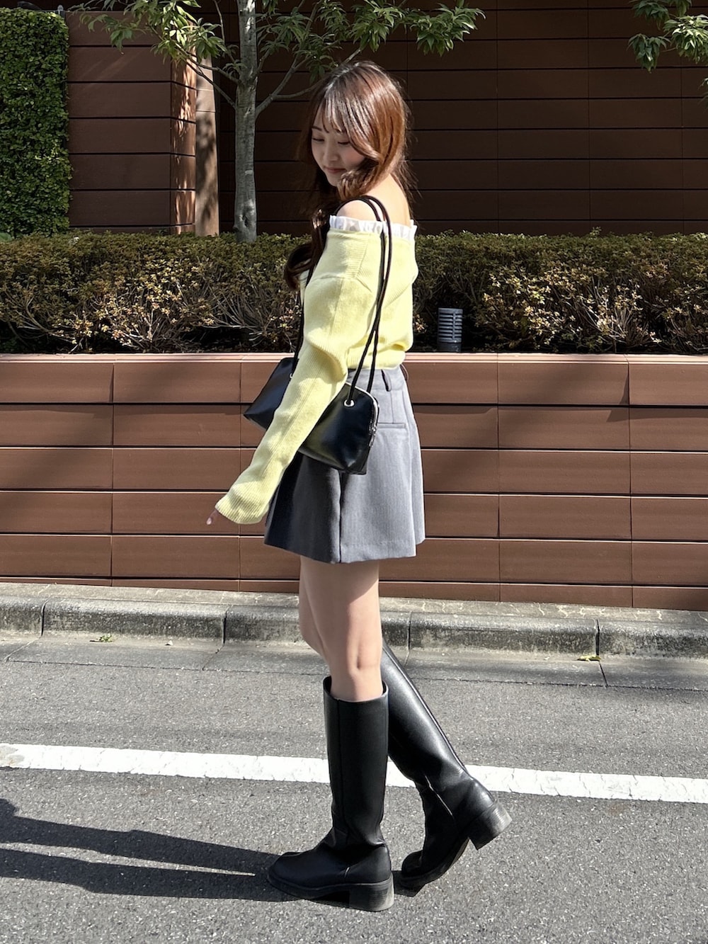 イエロー系のニット/セーター、ブラック系のショルダーバッグを着用したレディースの春コーディネートの2枚目の写真