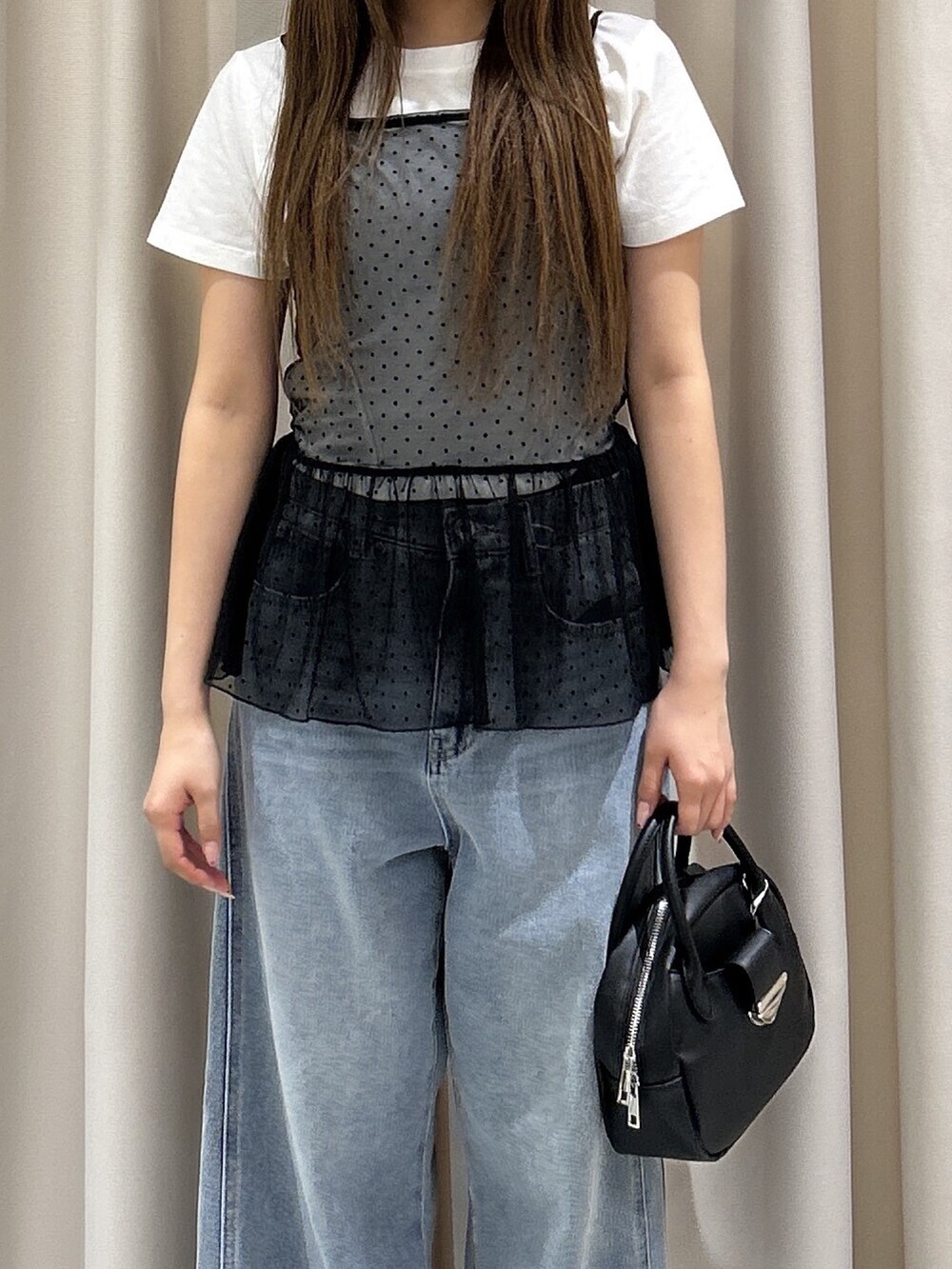 ブラック系のTシャツ/カットソー、ブラック系のハンドバッグ、ブルー系のデニムパンツを着用したレディースの夏コーディネートの3枚目の写真