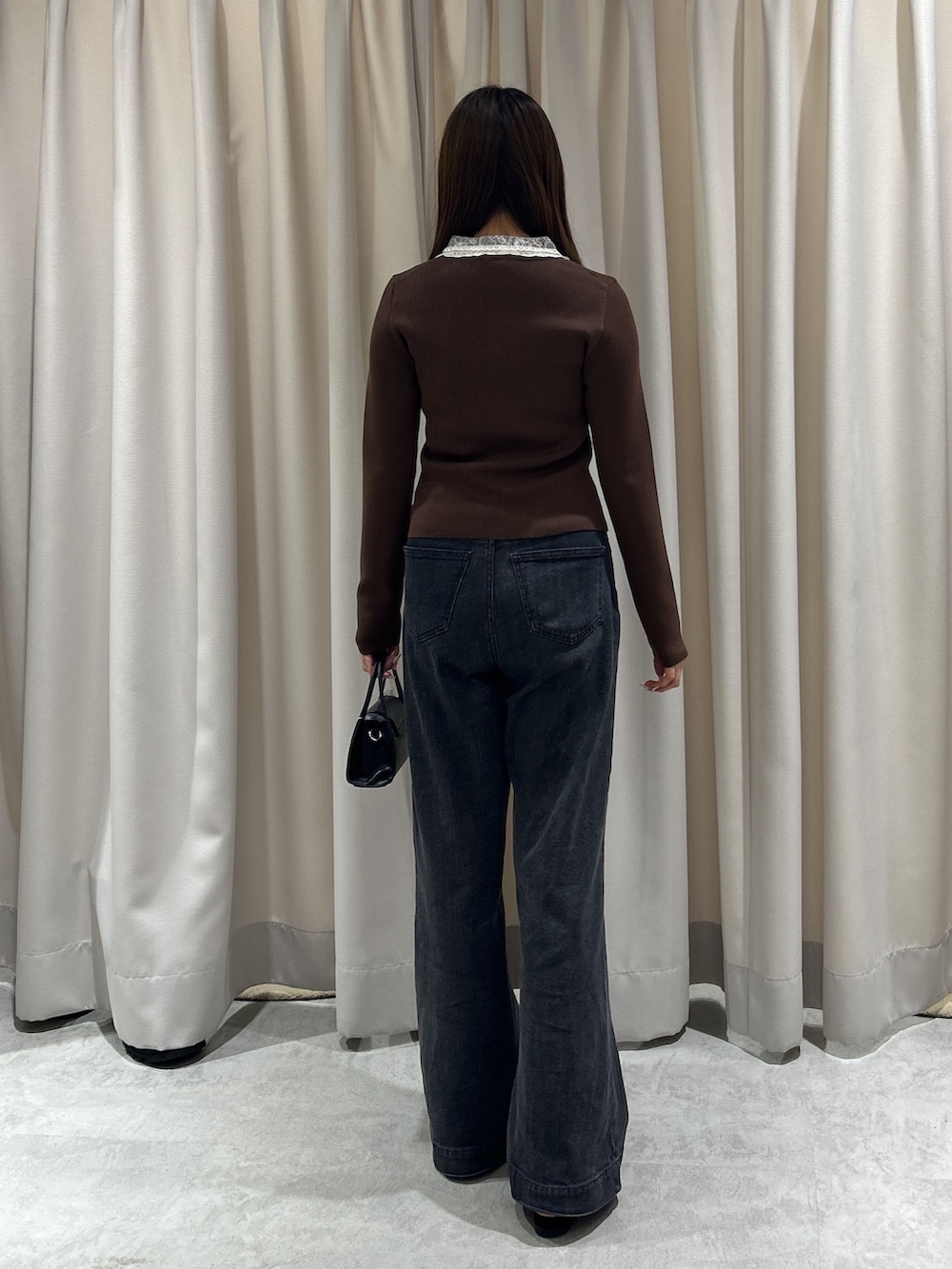 ブラウン系のニット/セーター、ブラック系のデニムパンツ、ブラック系のショルダーバッグを着用したレディースの秋コーディネートの3枚目の写真