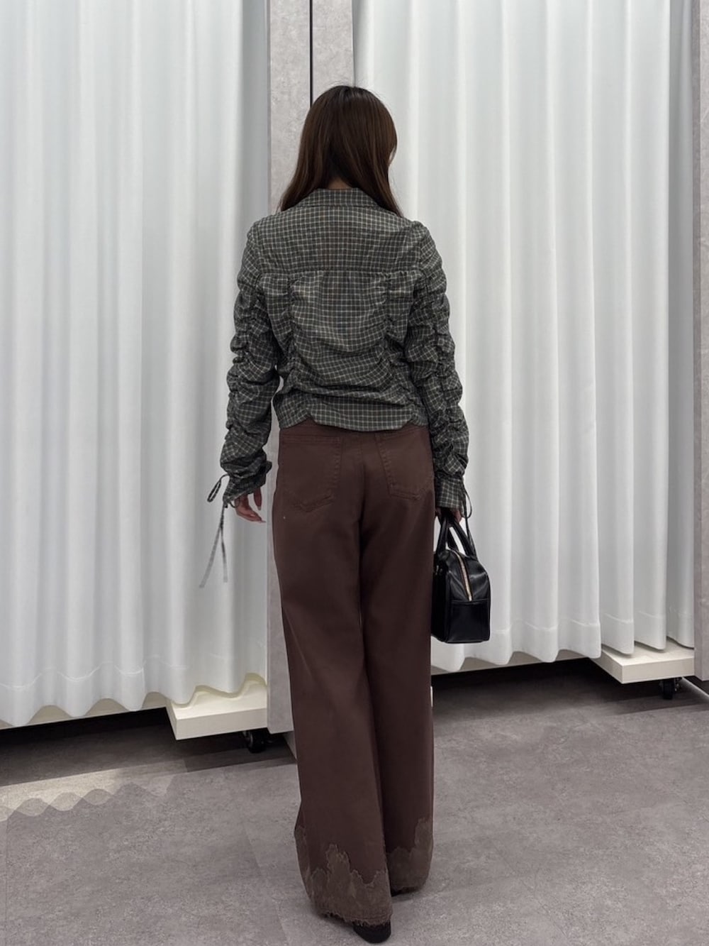 ブラック系のシャツ/ブラウス、ブラウン系のデニムパンツ、ブラック系のハンドバッグを着用したレディースの秋コーディネートの4枚目の写真