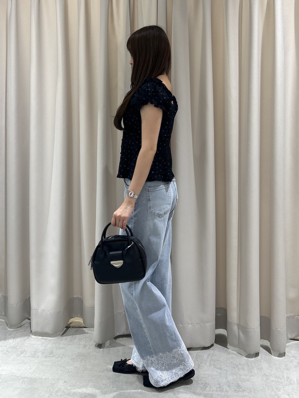 ブルー系のデニムパンツ、ブラック系のTシャツ/カットソー、ブラック系のハンドバッグを着用したレディースの夏コーディネートの2枚目の写真