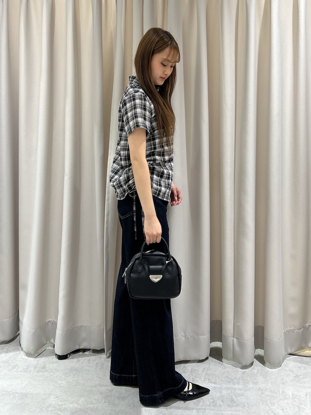 ブルー系のデニムパンツ、ブラック系のシャツ/ブラウス、ブラック系のハンドバッグを着用したレディースの夏コーディネートの3枚目の写真