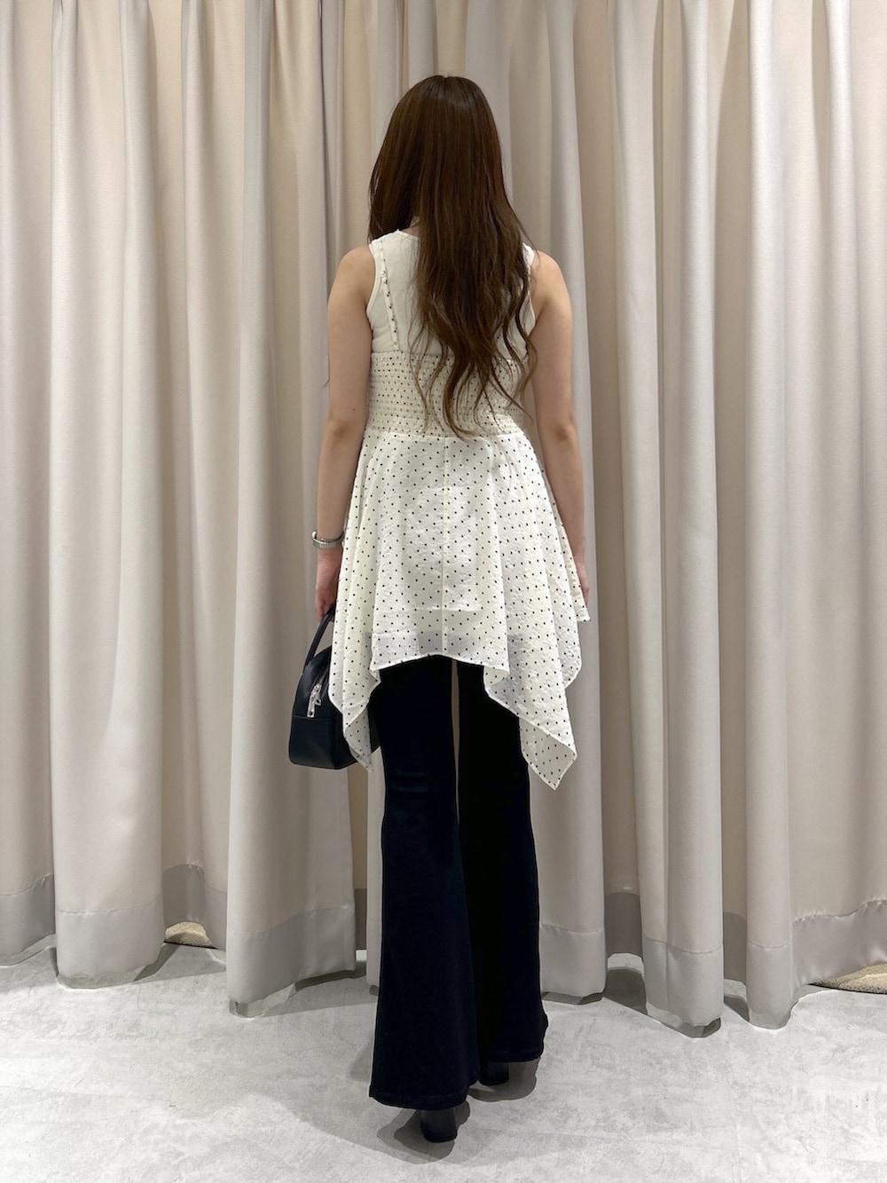 ホワイト系のワンピース、ブラック系のデニムパンツ、ブラック系のハンドバッグを着用したレディースの夏コーディネートの4枚目の写真