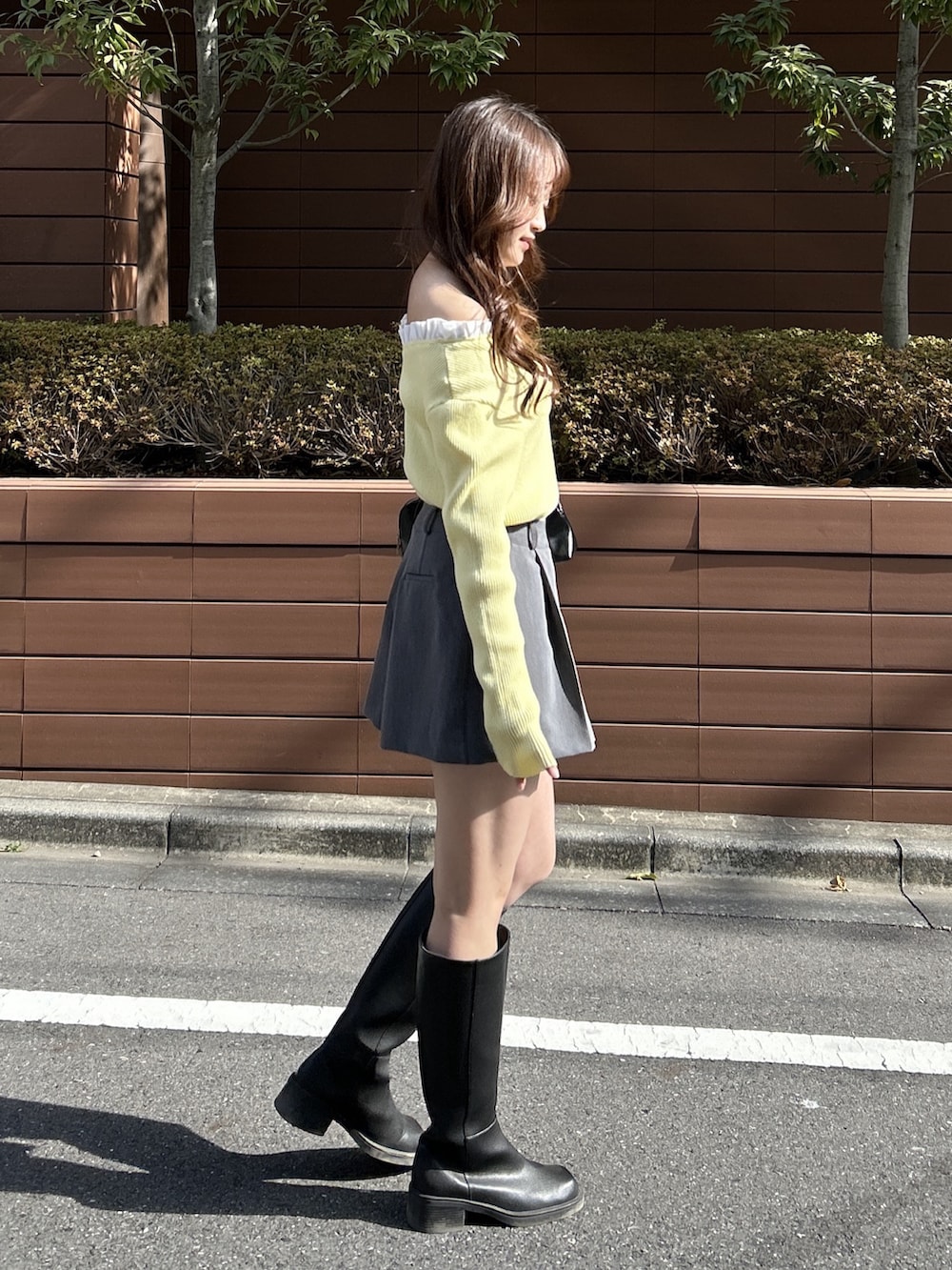 イエロー系のニット/セーター、ブラック系のショルダーバッグを着用したレディースの春コーディネートの3枚目の写真