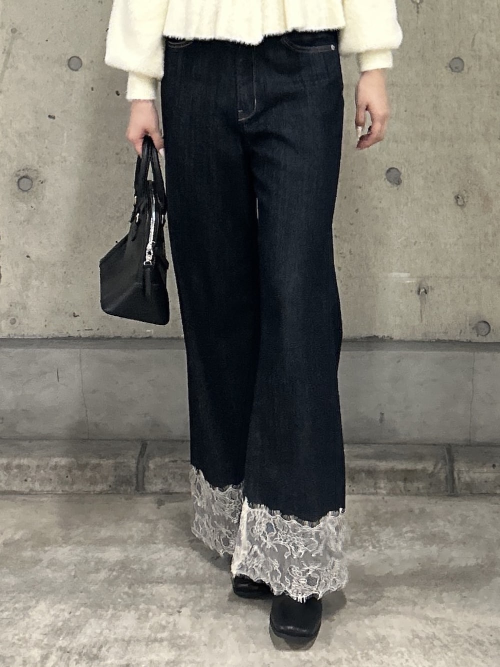ホワイト系のニット/セーター、ブルー系のデニムパンツ、ブラック系のショルダーバッグを着用したレディースの秋コーディネートの5枚目の写真