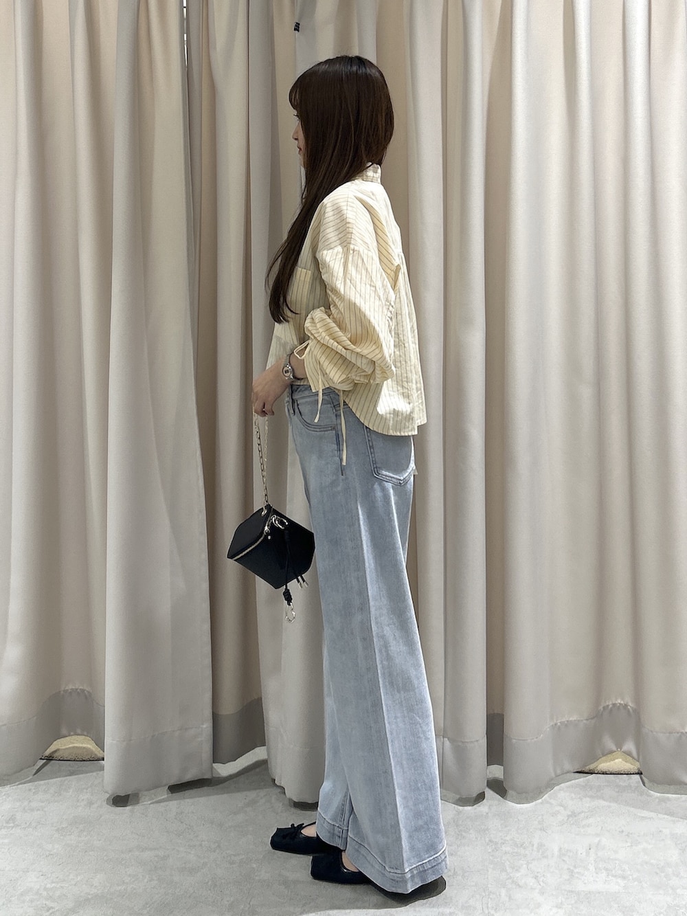 ホワイト系のシャツ/ブラウス、ブラック系のショルダーバッグ、ブルー系のデニムパンツを着用したレディースの秋コーディネートの2枚目の写真