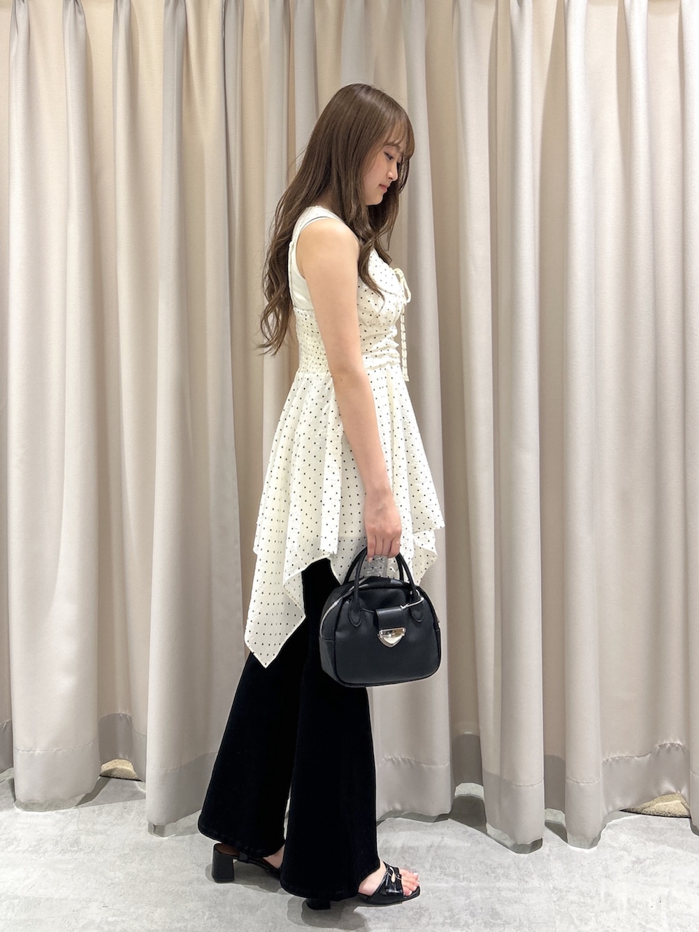 ホワイト系のワンピース、ブラック系のデニムパンツ、ブラック系のハンドバッグを着用したレディースの夏コーディネートの3枚目の写真