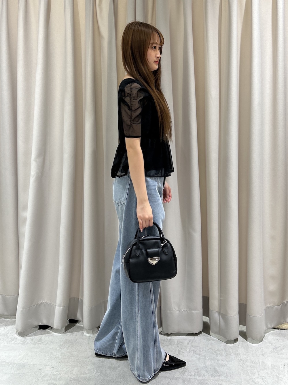 ブラック系のシャツ/ブラウス、ブルー系のデニムパンツ、ブラック系のハンドバッグを着用したレディースの夏コーディネートの2枚目の写真
