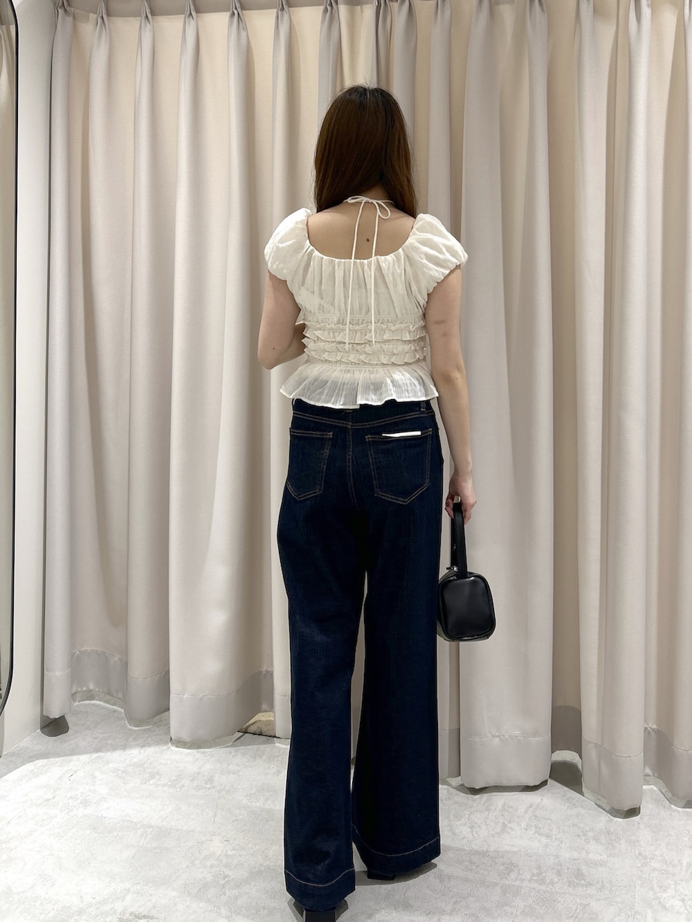 ブルー系のデニムパンツ、ブラック系のハンドバッグ、ホワイト系のシャツ/ブラウスを着用したレディースの春コーディネートの3枚目の写真