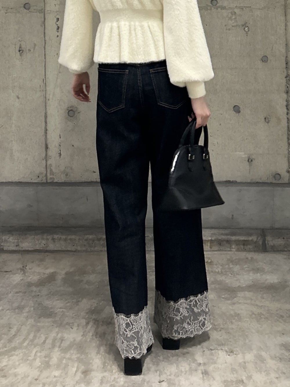 ホワイト系のニット/セーター、ブルー系のデニムパンツ、ブラック系のショルダーバッグを着用したレディースの秋コーディネートの6枚目の写真