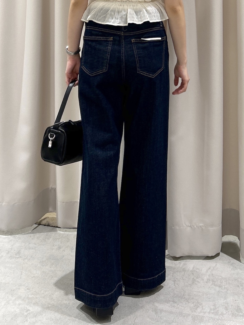 ブルー系のデニムパンツ、ブラック系のハンドバッグ、ホワイト系のシャツ/ブラウスを着用したレディースの春コーディネートの5枚目の写真