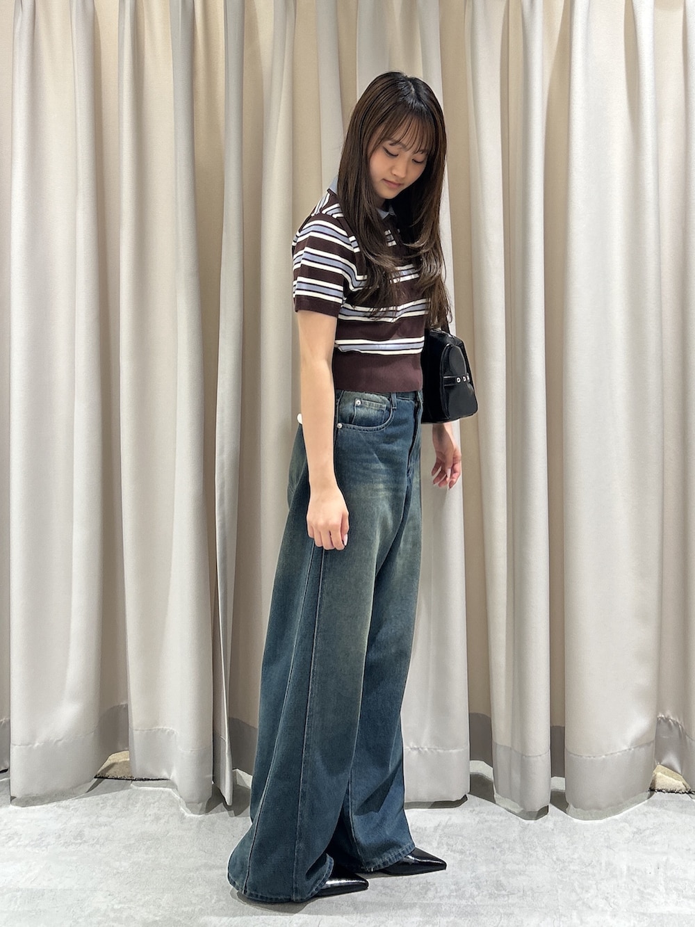 ブラウン系のニット/セーター、ブルー系のデニムパンツ、ブラック系のショルダーバッグを着用したレディースの夏コーディネートの3枚目の写真