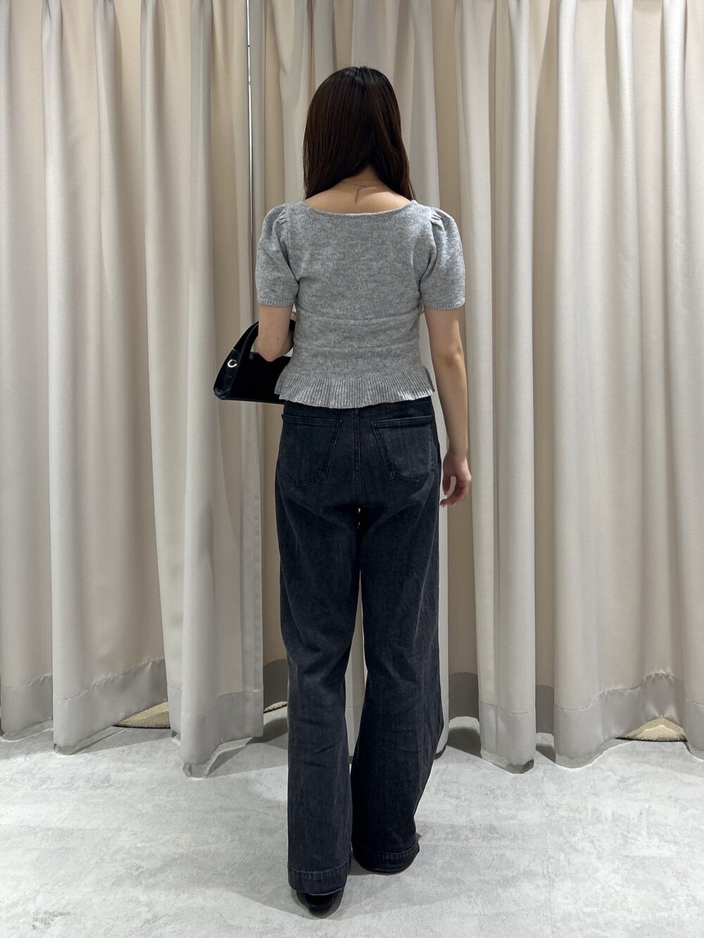 グレー系のニット/セーター、ブラック系のデニムパンツ、ブラック系のショルダーバッグを着用したレディースの夏コーディネートの4枚目の写真
