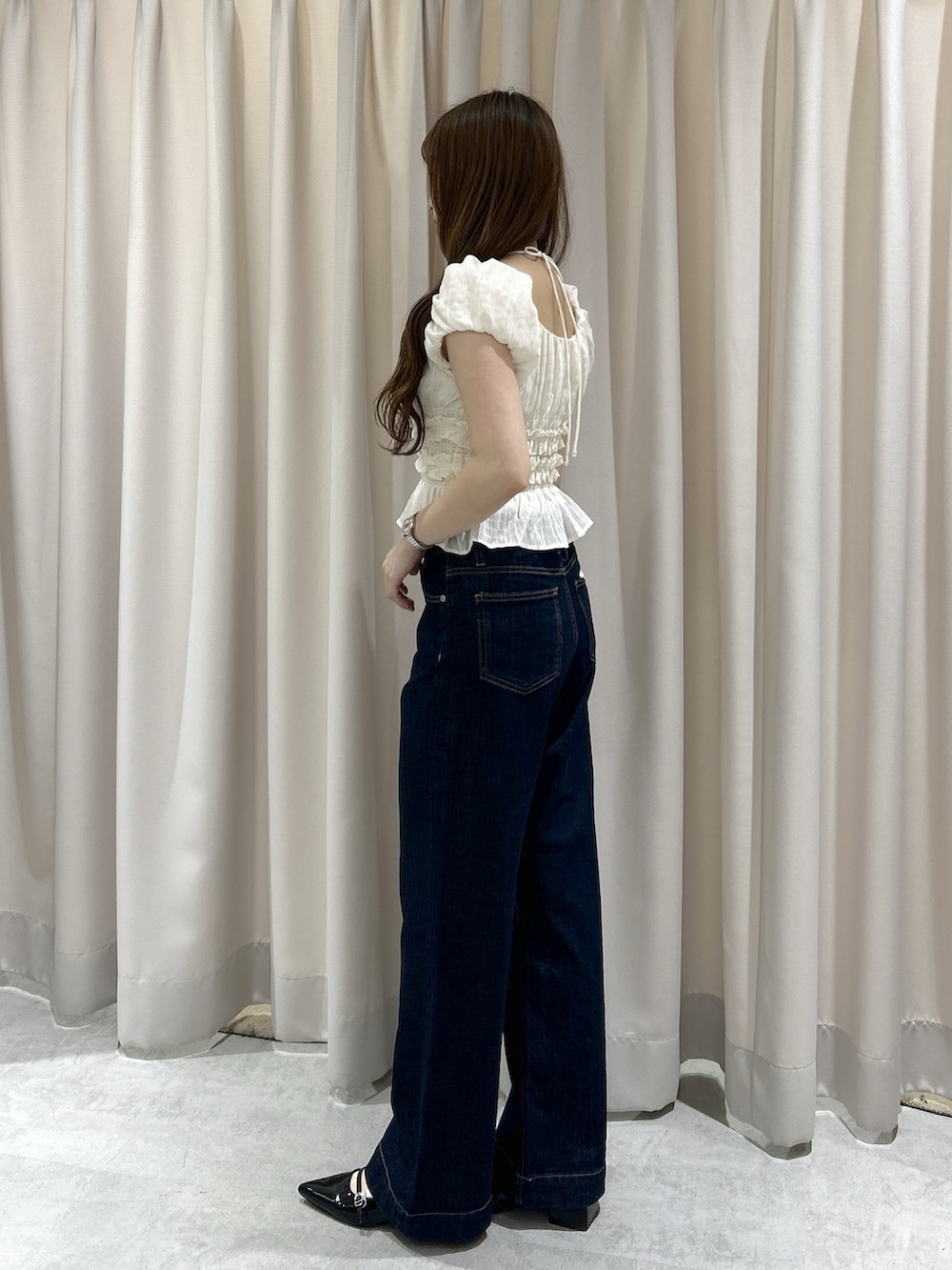 ブルー系のデニムパンツ、ブラック系のハンドバッグ、ホワイト系のシャツ/ブラウスを着用したレディースの春コーディネートの2枚目の写真