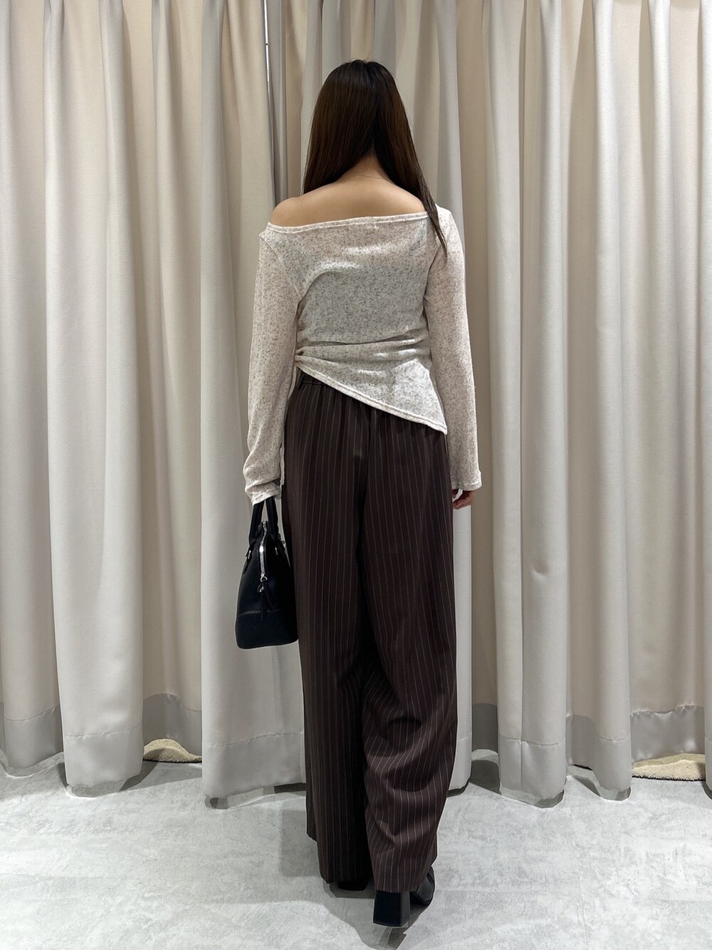ブラウン系のTシャツ/カットソー、ブラウン系のスラックス、ブラック系のショルダーバッグを着用したレディースの秋コーディネートの4枚目の写真