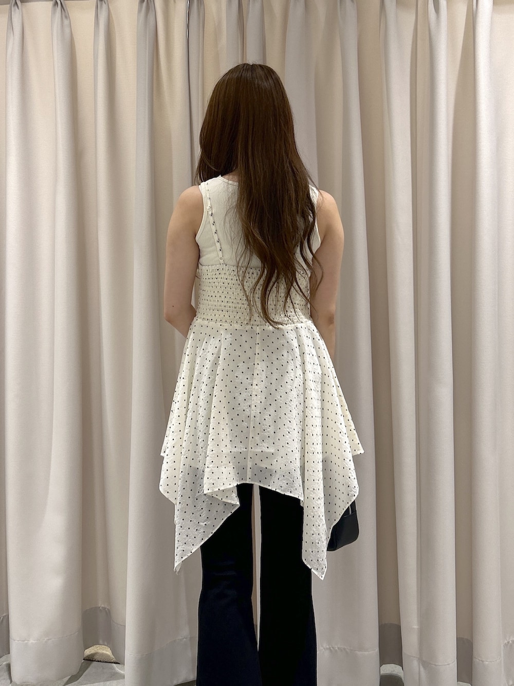 ホワイト系のワンピース、ブラック系のデニムパンツ、ブラック系のハンドバッグを着用したレディースの夏コーディネートの6枚目の写真