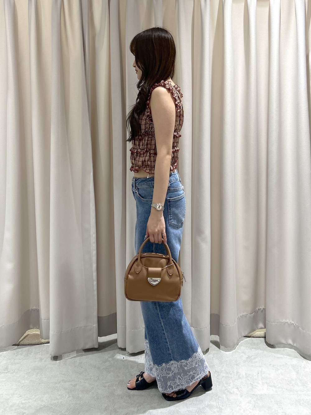 レッド系のシャツ/ブラウス、ブルー系のデニムパンツ、ブラウン系のハンドバッグを着用したレディースの夏コーディネートの2枚目の写真