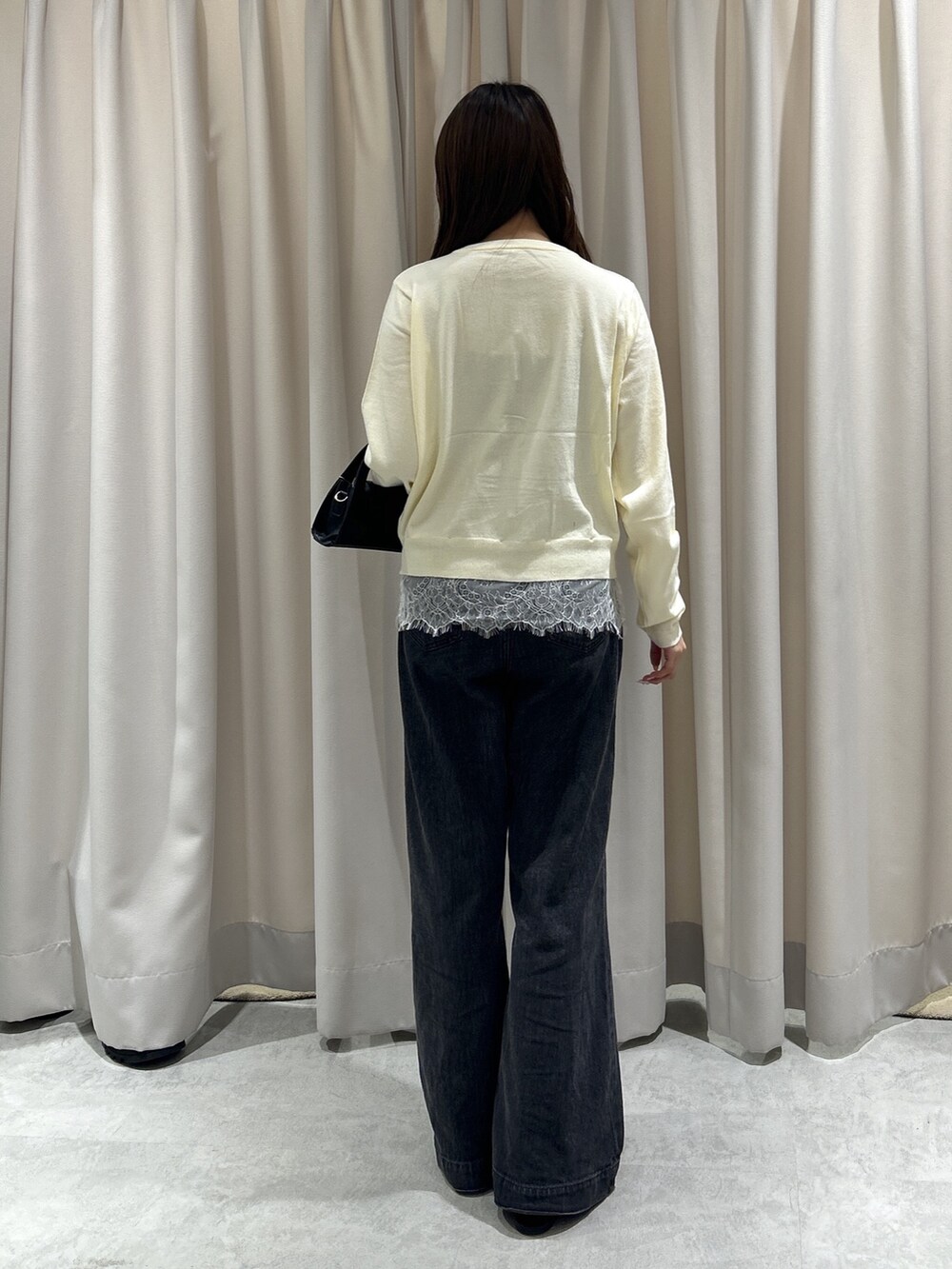ホワイト系のニット/セーター、ブラック系のデニムパンツ、ブラック系のショルダーバッグを着用したレディースの夏コーディネートの4枚目の写真