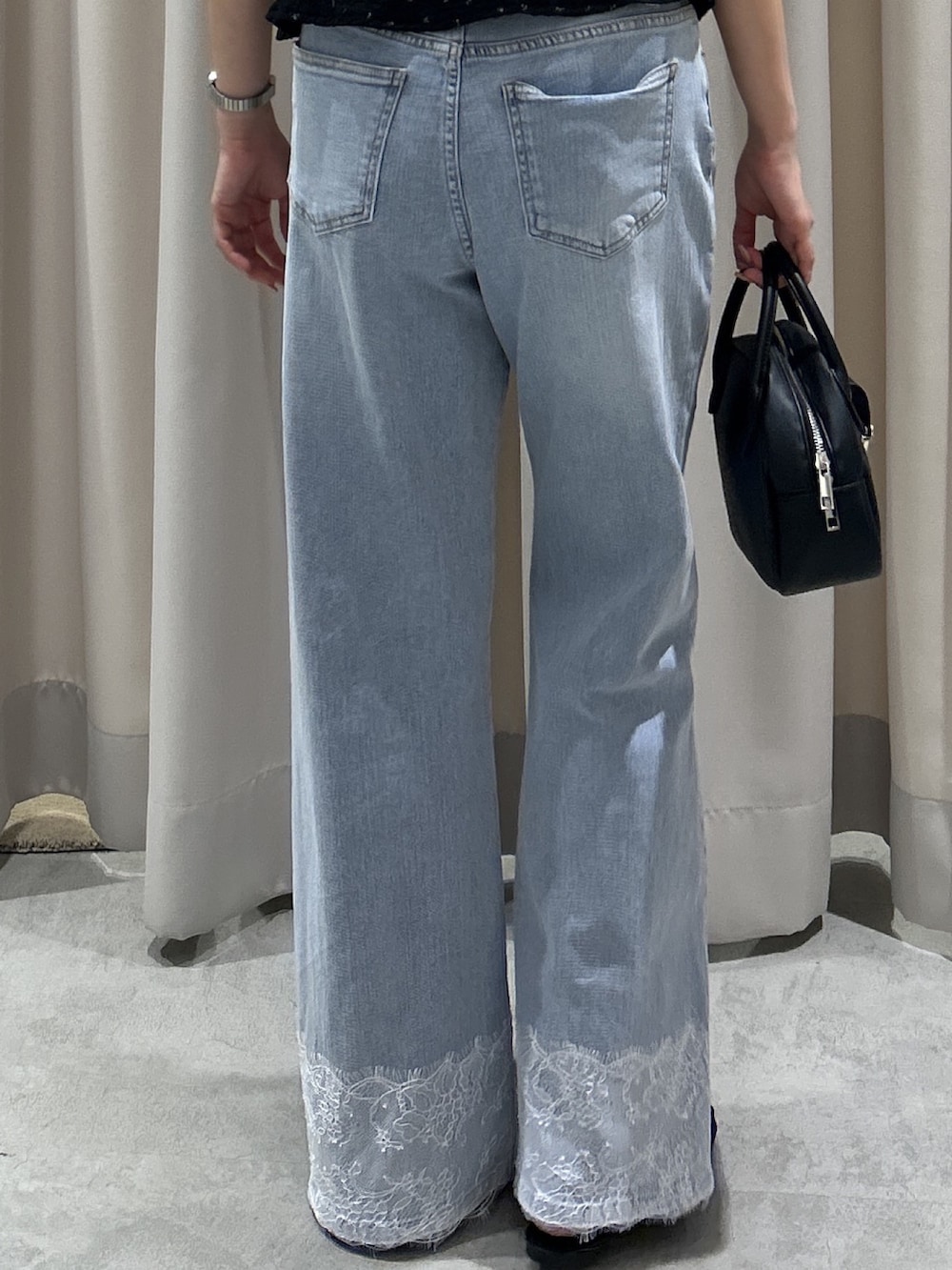 ブルー系のデニムパンツ、ブラック系のTシャツ/カットソー、ブラック系のハンドバッグを着用したレディースの夏コーディネートの6枚目の写真
