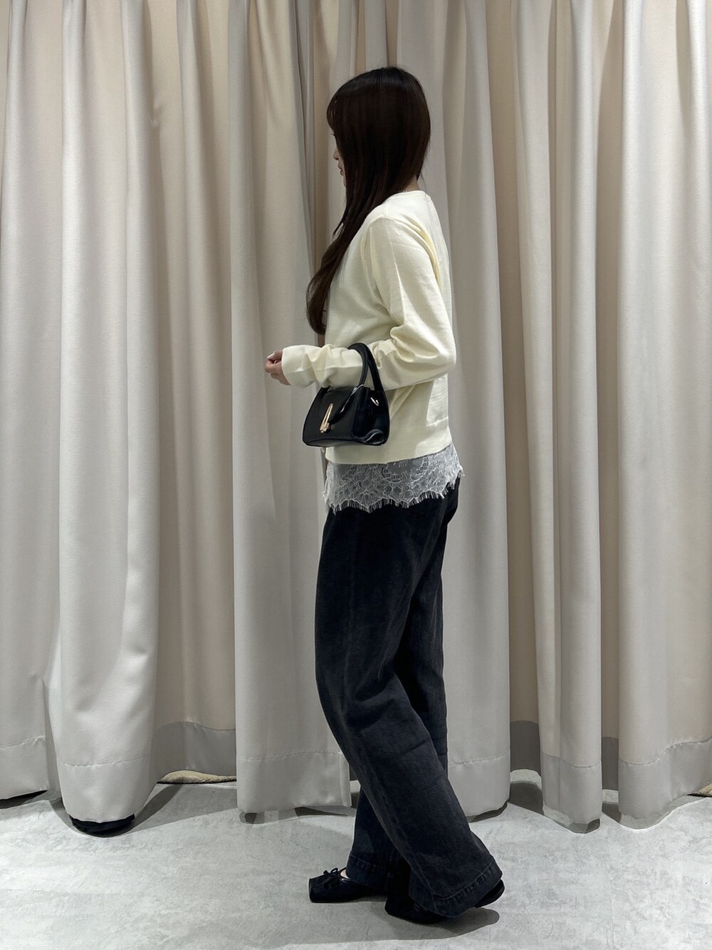 ホワイト系のニット/セーター、ブラック系のデニムパンツ、ブラック系のショルダーバッグを着用したレディースの夏コーディネートの2枚目の写真